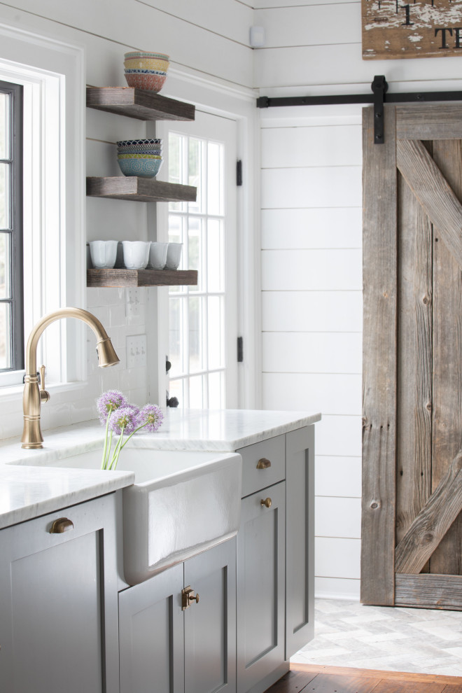 Inspiration for a large beach style single-wall eat-in kitchen in Other with a farmhouse sink, shaker cabinets, grey cabinets, marble benchtops, white splashback, subway tile splashback, stainless steel appliances, medium hardwood floors, with island, brown floor and grey benchtop.