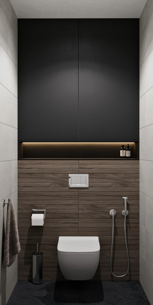 Bild på ett litet funkis toalett, med svarta skåp, en vägghängd toalettstol, grå kakel, grå väggar, klinkergolv i porslin, ett väggmonterat handfat, svart golv och porslinskakel
