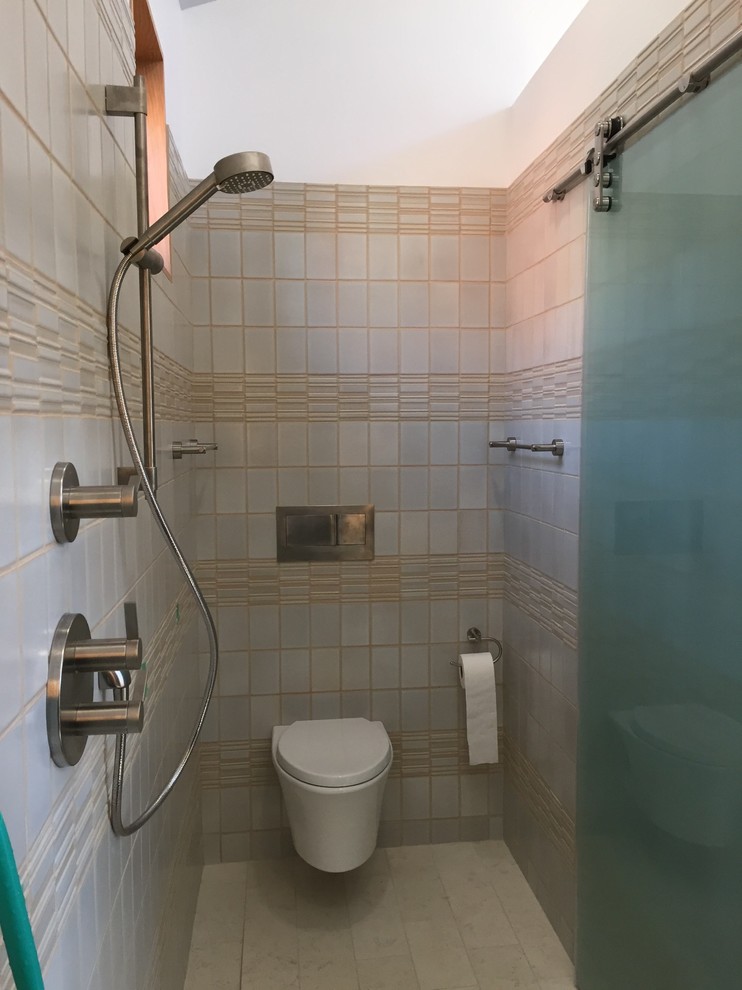 Photo of a small modern bathroom in Portland with an integrated sink, flat-panel cabinets, dark wood cabinets, solid surface benchtops, an open shower, a wall-mount toilet, beige tile, porcelain tile, beige walls and ceramic floors.