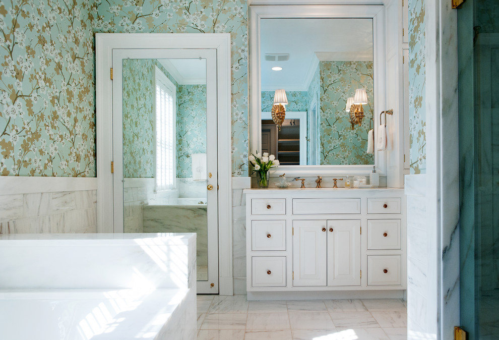 This is an example of a mid-sized traditional bathroom in Nashville with raised-panel cabinets, white cabinets, white tile, an undermount sink, marble benchtops, a drop-in tub, an alcove shower, marble floors and multi-coloured walls.