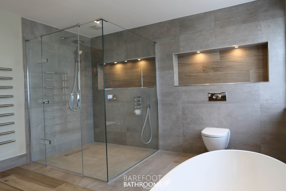 Design ideas for an expansive contemporary kids wet room bathroom in Essex with flat-panel cabinets, medium wood cabinets, a freestanding tub, a wall-mount toilet, gray tile, porcelain tile, green walls, porcelain floors, a vessel sink, engineered quartz benchtops, grey floor, a hinged shower door and black benchtops.