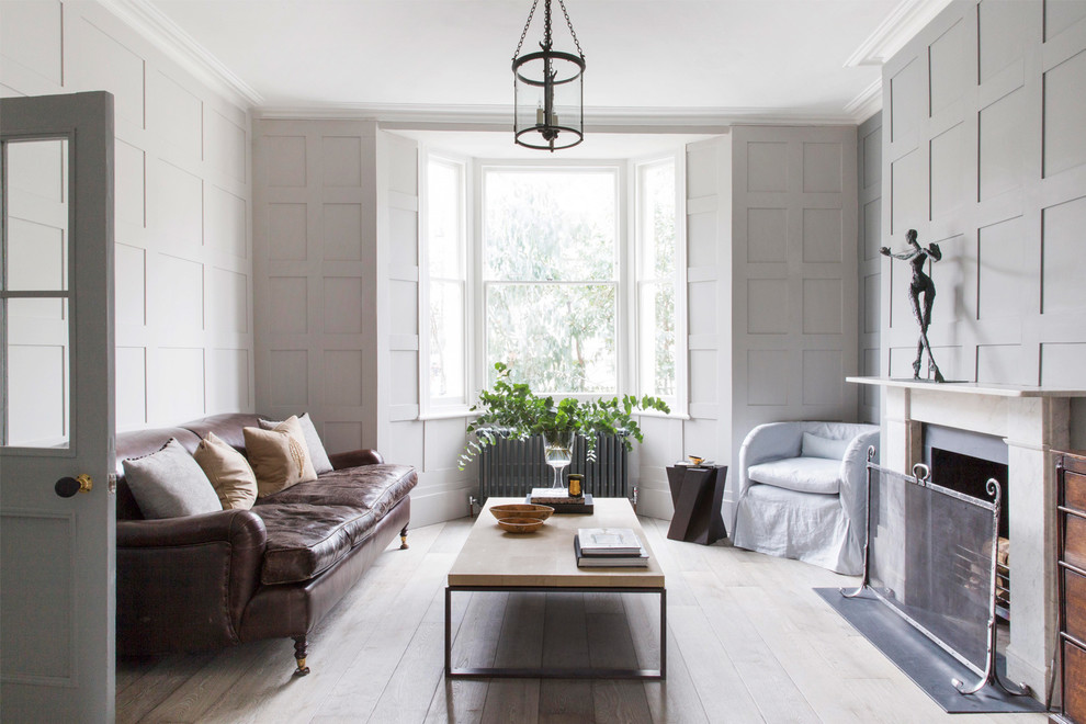 Inspiration for a mid-sized traditional formal enclosed living room in London with grey walls, light hardwood floors, a standard fireplace and white floor.