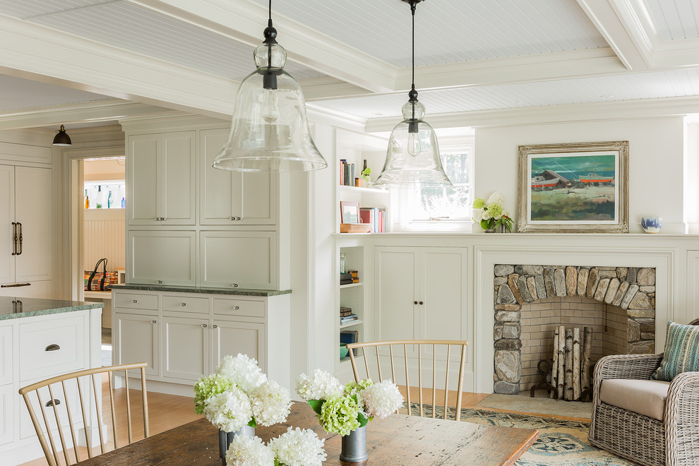 Mid-sized cottage light wood floor and beige floor kitchen/dining room combo photo in Boston with white walls, a standard fireplace and a stone fireplace