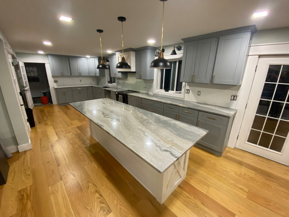 This is an example of a country l-shaped kitchen pantry in Bridgeport with a double-bowl sink, shaker cabinets, blue cabinets, granite benchtops, stainless steel appliances, medium hardwood floors, with island, brown floor and blue benchtop.