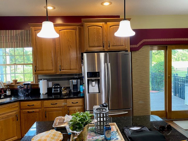 Open concept kitchen - large transitional l-shaped laminate floor and brown floor open concept kitchen idea with an undermount sink, flat-panel cabinets, white cabinets, quartz countertops, white backsplash, ceramic backsplash, stainless steel appliances, an island and white countertops