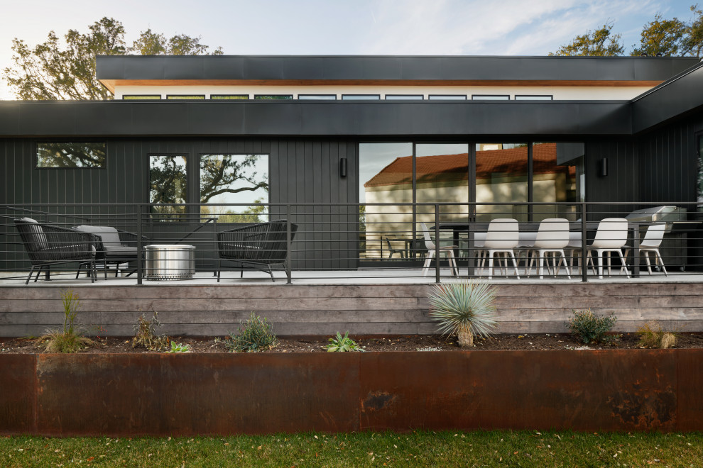 Inspiration pour une grande façade de maison beige vintage en planches et couvre-joints de plain-pied avec un revêtement mixte, un toit plat, un toit en métal et un toit noir.
