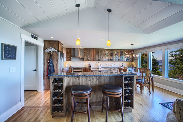 Inspiration for a large rustic u-shaped light wood floor eat-in kitchen remodel in Seattle with a double-bowl sink, recessed-panel cabinets, distressed cabinets, quartz countertops, beige backsplash, ceramic backsplash, stainless steel appliances and an island