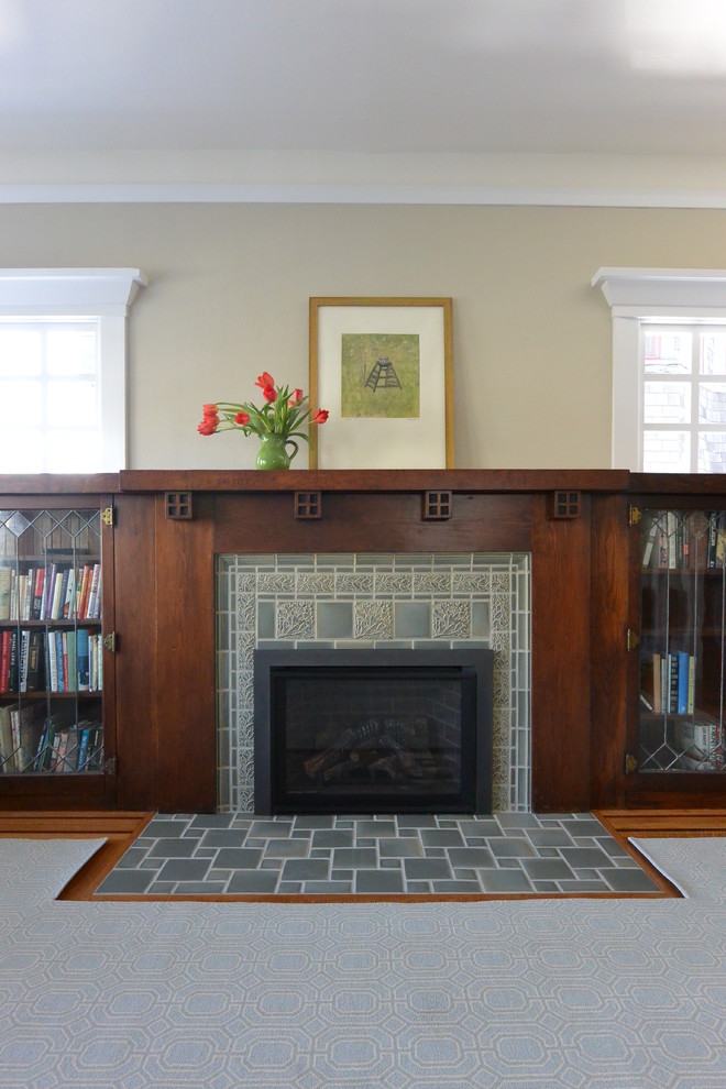 This is an example of a mid-sized arts and crafts enclosed living room in San Francisco with a library, beige walls, light hardwood floors, a standard fireplace, a tile fireplace surround and brown floor.