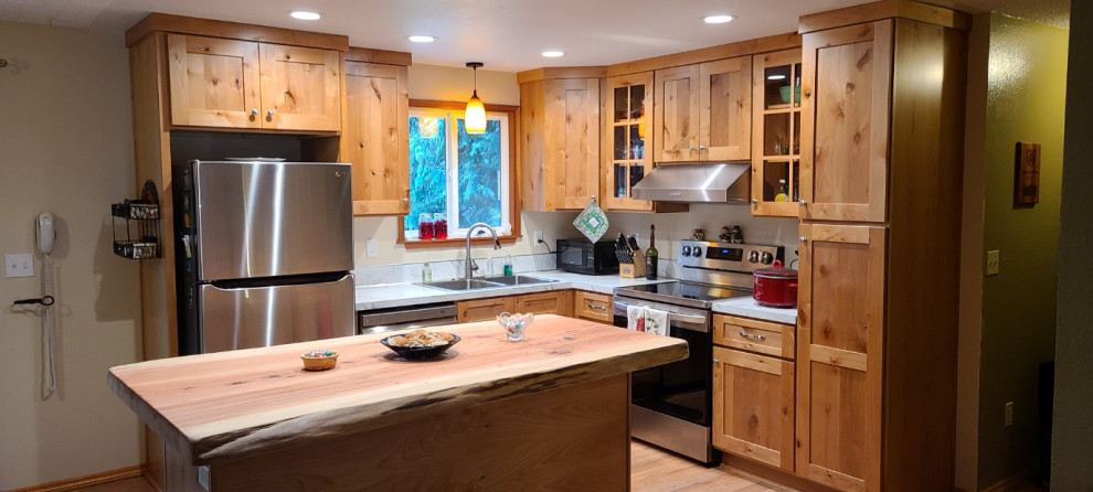 Photo of a rustic kitchen/diner in Seattle with flat-panel cabinets, medium wood cabinets, wood worktops, stainless steel appliances and an island.