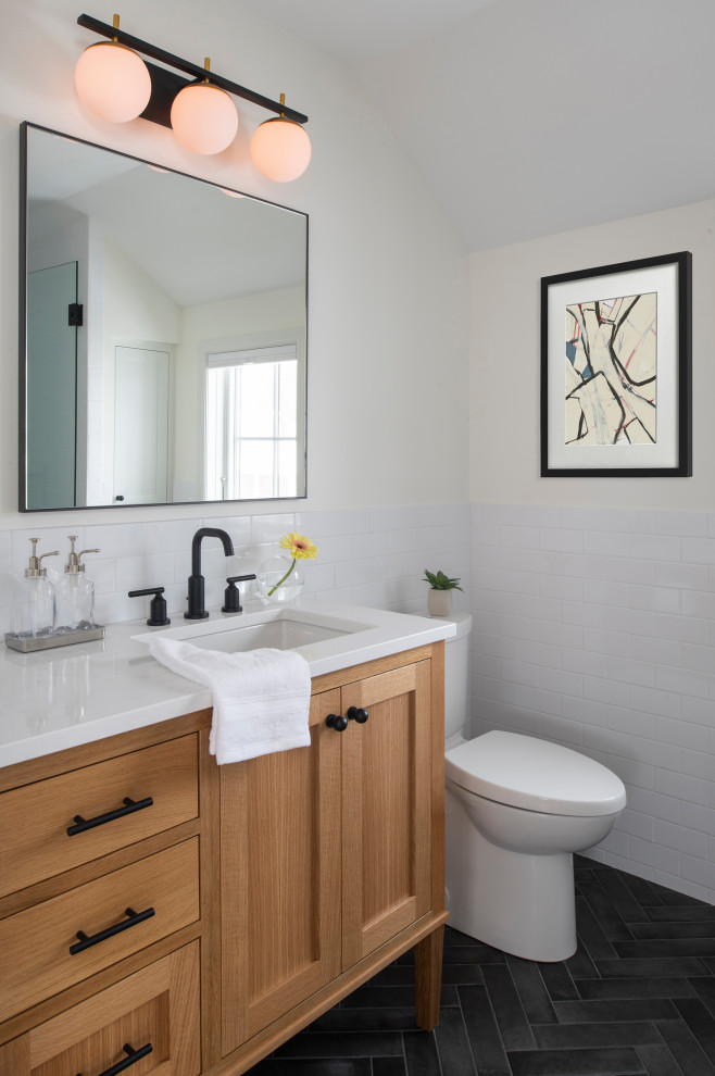 Klassisk inredning av ett litet vit vitt en-suite badrum, med släta luckor, skåp i mellenmörkt trä, vit kakel, keramikplattor, vita väggar, klinkergolv i keramik, ett undermonterad handfat, bänkskiva i akrylsten och svart golv