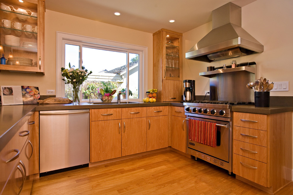 Photo of a mid-sized modern u-shaped open plan kitchen in San Francisco with an undermount sink, flat-panel cabinets, light wood cabinets, concrete benchtops, stainless steel appliances, medium hardwood floors and metallic splashback.