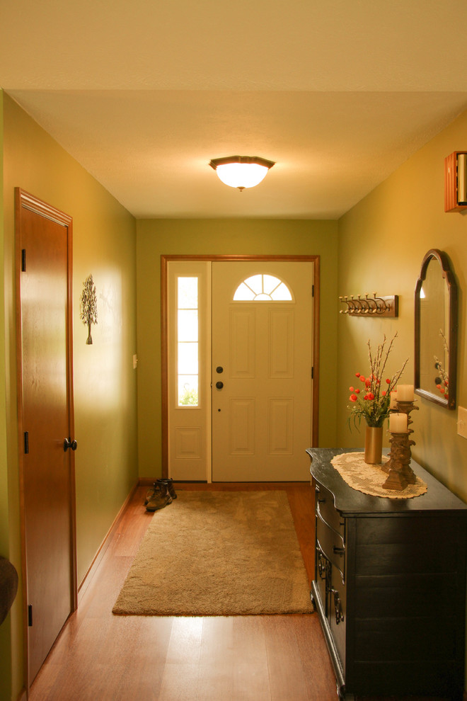 This is an example of a mid-sized traditional front door in Other with a single front door, a white front door, green walls, brown floor and laminate floors.