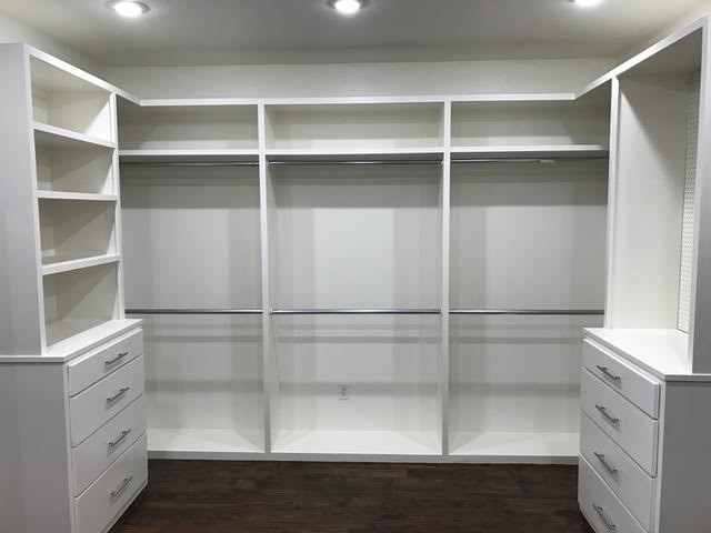 This is an example of a large traditional gender-neutral walk-in wardrobe in New Orleans with open cabinets, white cabinets and dark hardwood floors.