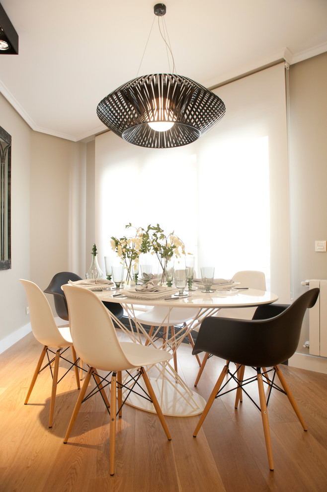 Photo of a mid-sized contemporary separate dining room in Bilbao with medium hardwood floors, no fireplace and white walls.