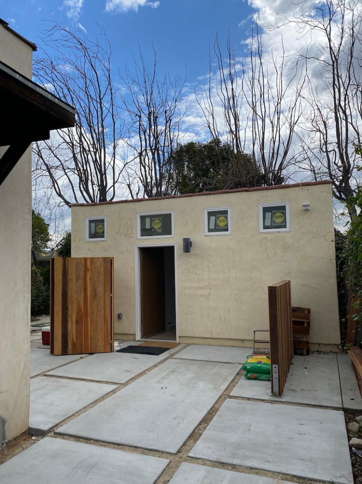 Immagine di un piccolo giardino esposto in pieno sole davanti casa in primavera con pavimentazioni in cemento e recinzione in legno