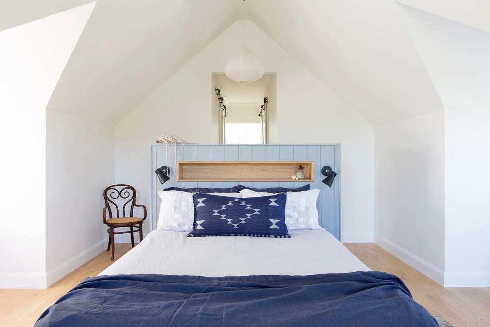 Photo of a small country guest bedroom in Wollongong with white walls, light hardwood floors and brown floor.