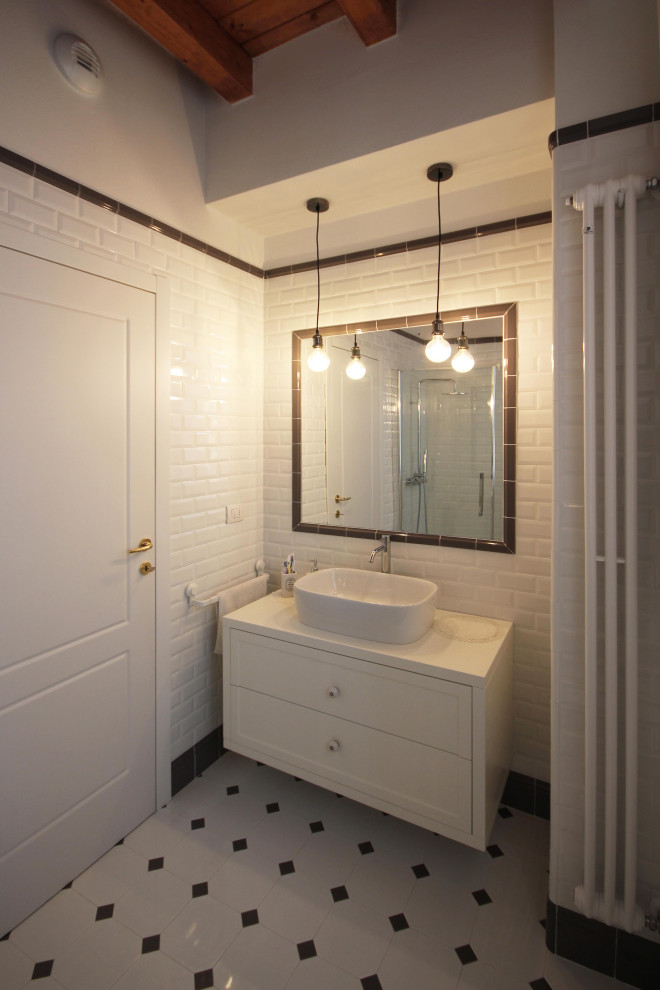 Photo of a mid-sized country 3/4 bathroom in Milan with recessed-panel cabinets, white cabinets, a corner shower, a two-piece toilet, black and white tile, subway tile, white walls, mosaic tile floors, a vessel sink, wood benchtops, multi-coloured floor, a sliding shower screen, white benchtops, a single vanity, a freestanding vanity, exposed beam and brick walls.