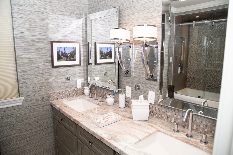 This is an example of a mid-sized contemporary kids bathroom in Houston with furniture-like cabinets, grey cabinets, an alcove tub, a shower/bathtub combo, a two-piece toilet, gray tile, mosaic tile, grey walls, porcelain floors, an undermount sink, marble benchtops, beige floor, a sliding shower screen and grey benchtops.