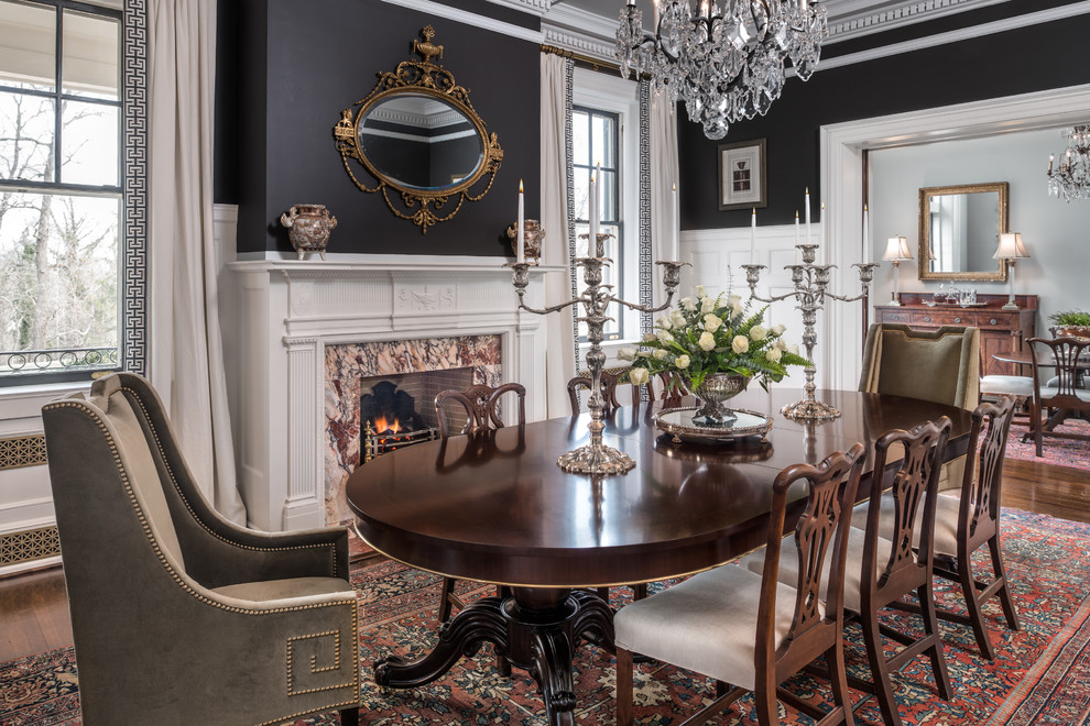 This is an example of a traditional separate dining room in Other with black walls, dark hardwood floors, a standard fireplace, a stone fireplace surround and brown floor.