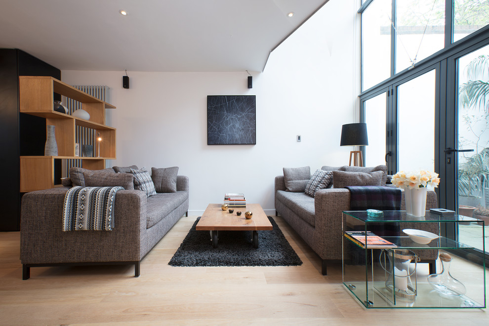 This is an example of a medium sized contemporary enclosed living room in London with white walls, no tv and beige floors.