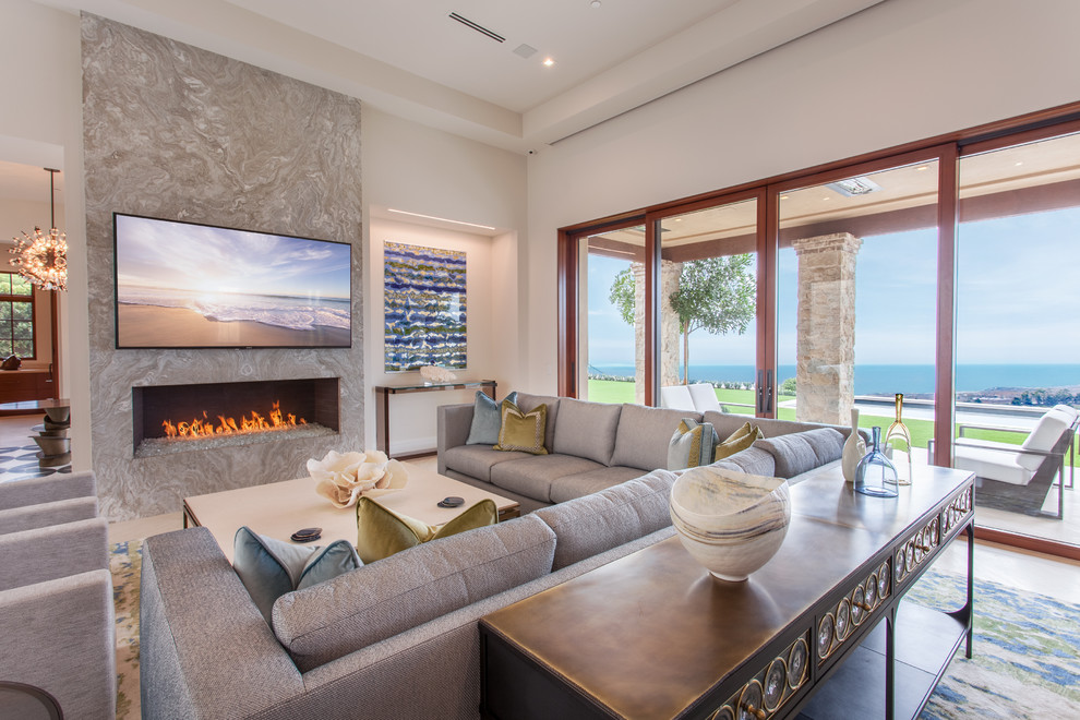 Mediterranean family room in Orange County with white walls, a ribbon fireplace, a stone fireplace surround and a wall-mounted tv.