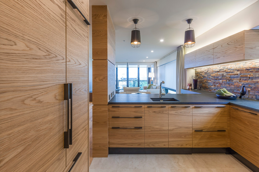 Mid-sized scandinavian u-shaped eat-in kitchen in Auckland with an undermount sink, flat-panel cabinets, light wood cabinets, granite benchtops, beige splashback, black appliances, light hardwood floors, with island and beige floor.