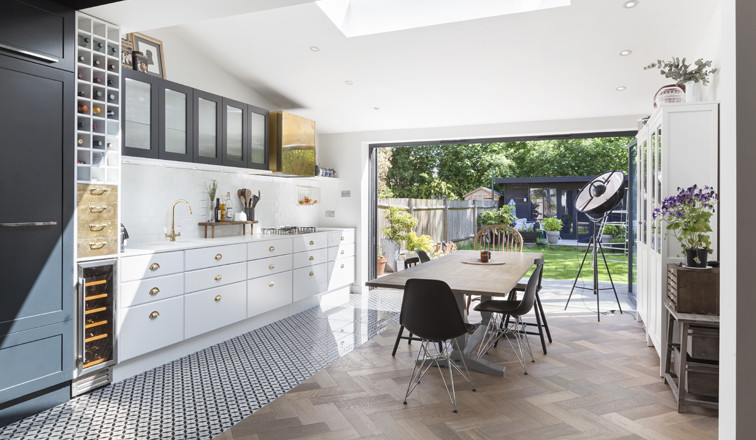 Design ideas for a mid-sized contemporary single-wall eat-in kitchen in London with an undermount sink, flat-panel cabinets, white cabinets, granite benchtops, white splashback, subway tile splashback, stainless steel appliances, medium hardwood floors and no island.