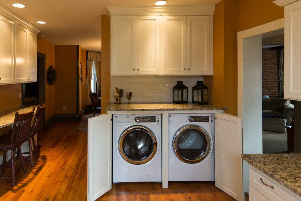 Design ideas for a mid-sized traditional u-shaped laundry room in Other with an undermount sink, shaker cabinets, white cabinets, granite benchtops, white splashback, subway tile splashback and light hardwood floors.
