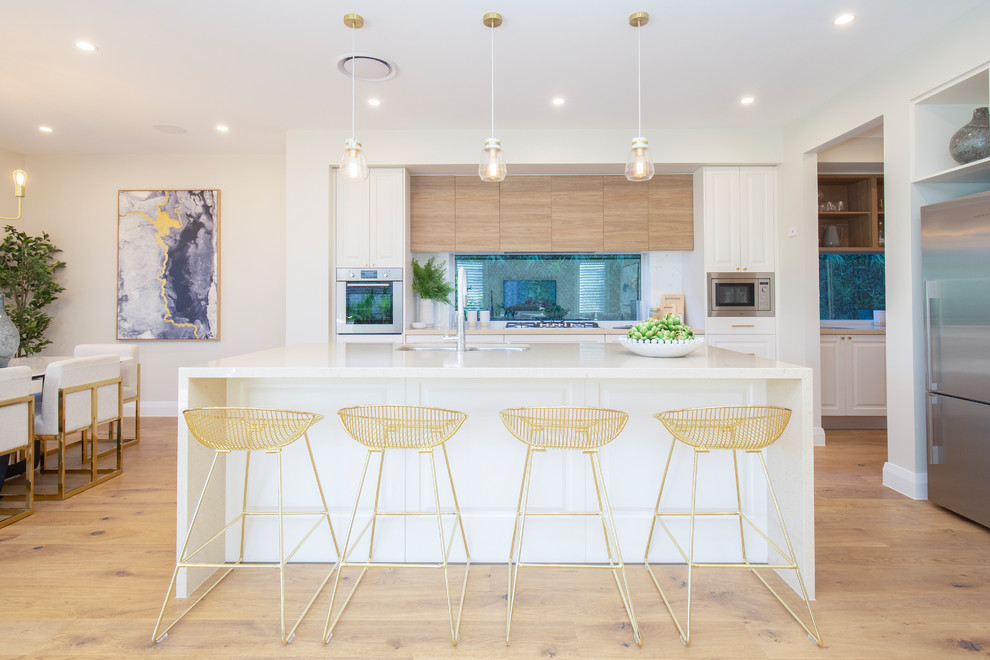 Contemporary eat-in kitchen in Central Coast with an undermount sink, raised-panel cabinets, white cabinets, window splashback, stainless steel appliances, light hardwood floors, with island, beige floor and white benchtop.