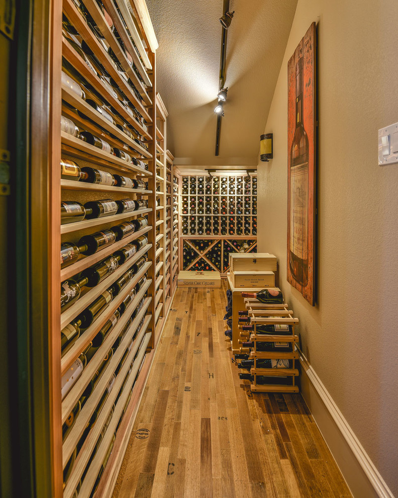 This is an example of a large traditional wine cellar in Dallas with light hardwood floors, display racks and yellow floor.