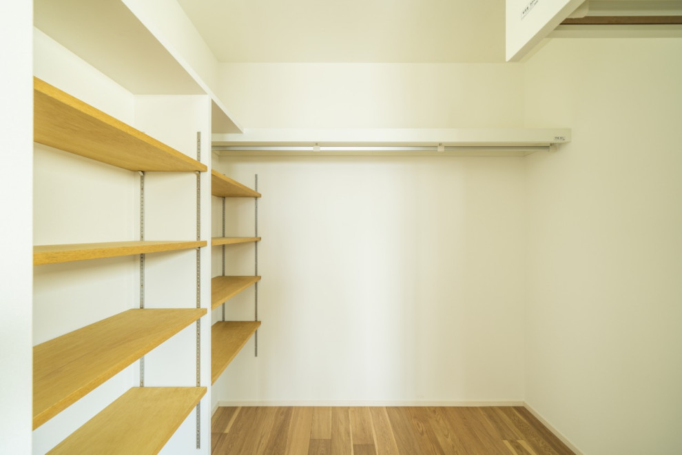 Medium sized modern gender neutral walk-in wardrobe in Other with open cabinets, light hardwood flooring, brown floors and a wallpapered ceiling.