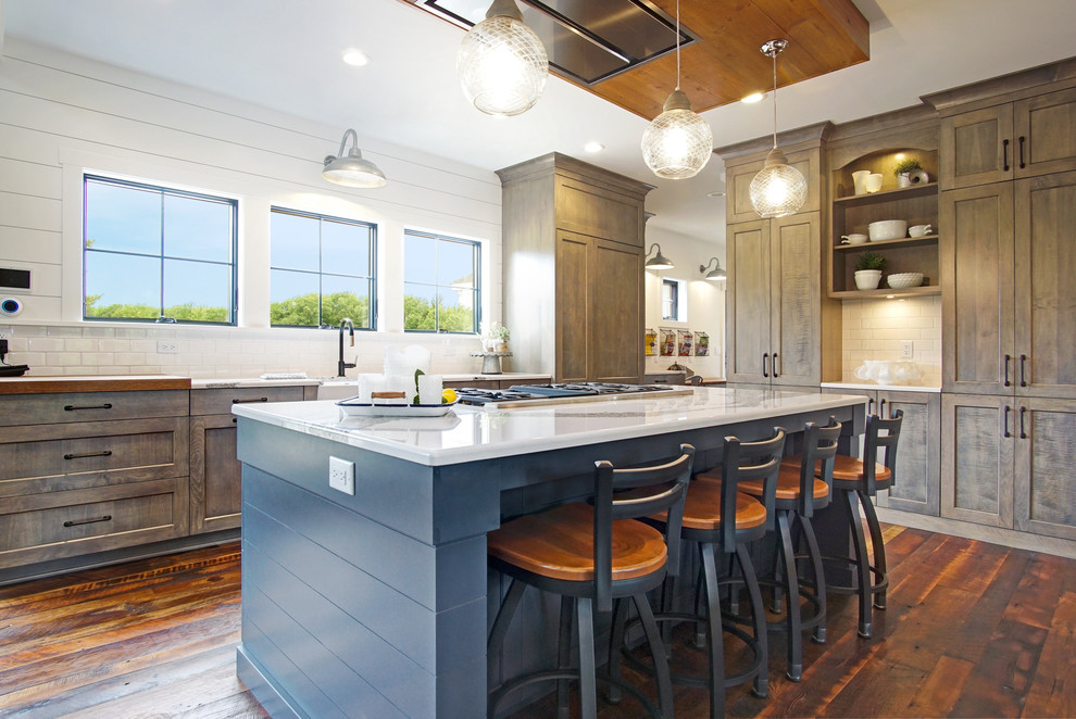 Country l-shaped kitchen in Grand Rapids with a farmhouse sink, shaker cabinets, dark wood cabinets, white splashback, subway tile splashback, dark hardwood floors, with island, brown floor and white benchtop.