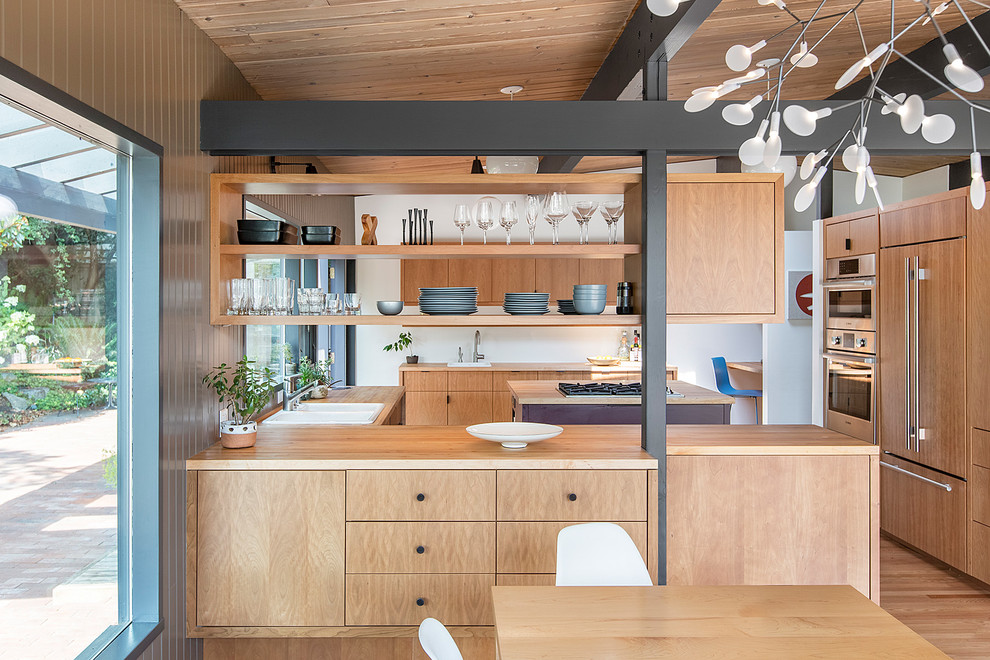 Design ideas for a midcentury u-shaped separate kitchen in Seattle with a drop-in sink, flat-panel cabinets, medium wood cabinets, wood benchtops, panelled appliances, medium hardwood floors, with island and brown floor.