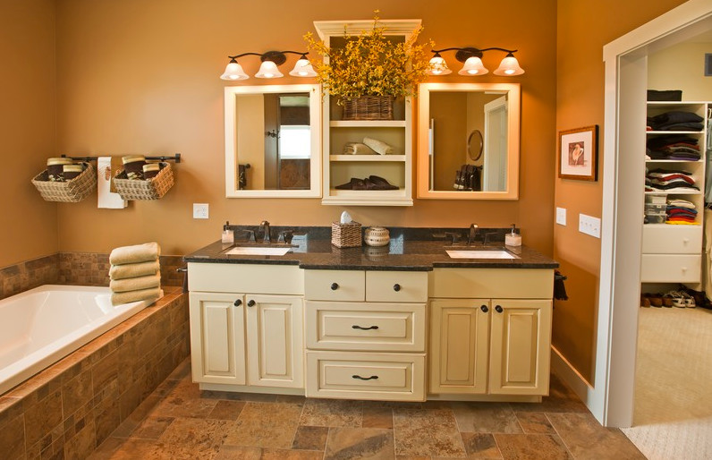 This is an example of a mid-sized arts and crafts master bathroom in Other with furniture-like cabinets, yellow cabinets, a drop-in tub, beige tile, porcelain tile, beige walls, porcelain floors, an undermount sink, granite benchtops and beige floor.