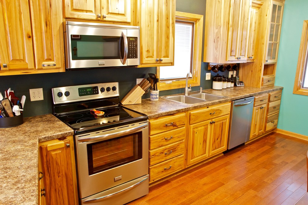 Inspiration for a small galley open concept kitchen remodel with a drop-in sink, raised-panel cabinets, light wood cabinets, laminate countertops, stainless steel appliances and a peninsula