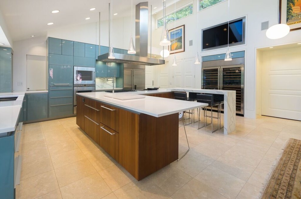 This is an example of a large contemporary u-shaped open plan kitchen in San Francisco with a double-bowl sink, flat-panel cabinets, blue cabinets, limestone benchtops, multi-coloured splashback, glass sheet splashback, stainless steel appliances, limestone floors, with island and beige floor.