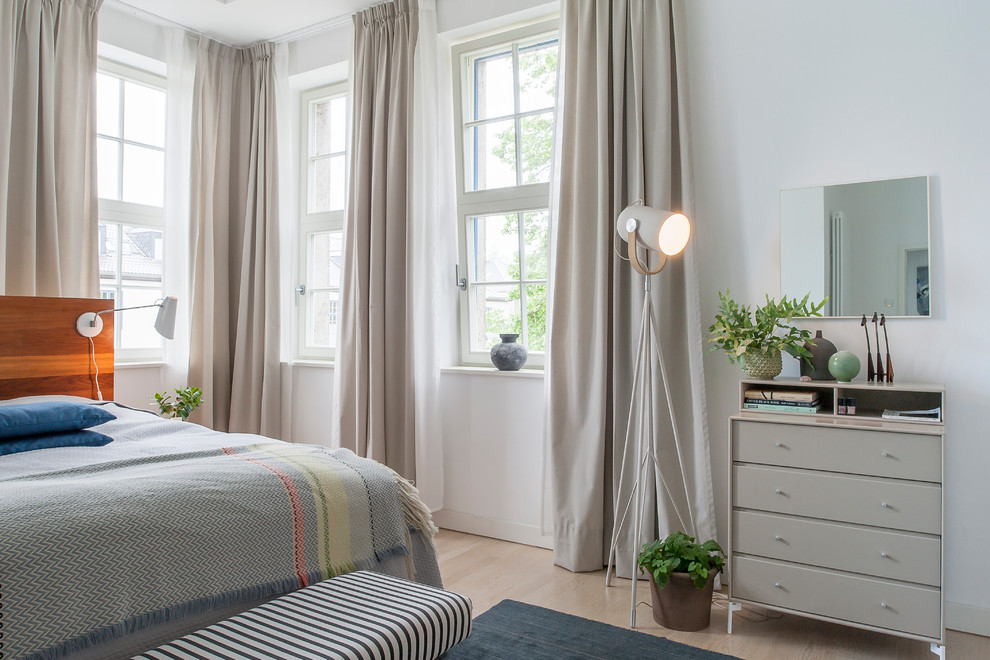 Photo of a mid-sized scandinavian bedroom in Berlin with white walls, light hardwood floors and beige floor.