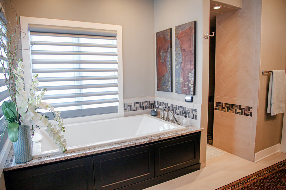This is an example of a mid-sized eclectic master bathroom in Milwaukee with shaker cabinets, dark wood cabinets, granite benchtops, a drop-in tub, beige tile, porcelain tile, beige walls and porcelain floors.