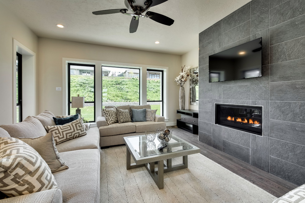 This is an example of a mid-sized modern open concept family room in Boise with white walls, light hardwood floors, a standard fireplace, a tile fireplace surround, a wall-mounted tv and multi-coloured floor.