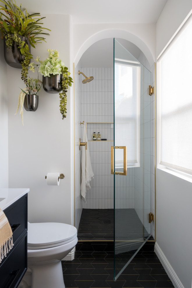 Стильный дизайн: маленькая ванная комната с фасадами с декоративным кантом, черными фасадами, душем в нише, раздельным унитазом, белой плиткой, керамической плиткой, белыми стенами, полом из керамической плитки, душевой кабиной, монолитной раковиной, столешницей из искусственного камня, черным полом, душем с распашными дверями, белой столешницей, нишей, тумбой под одну раковину и подвесной тумбой для на участке и в саду - последний тренд