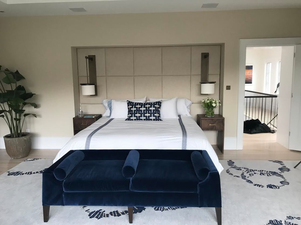 Photo of a large contemporary master bedroom in DC Metro with beige walls, light hardwood floors, a standard fireplace, a concrete fireplace surround and beige floor.
