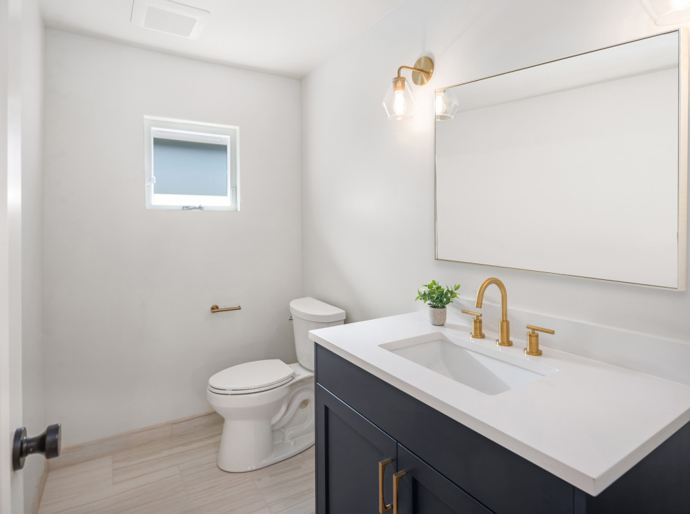Idéer för att renovera ett mellanstort retro vit vitt toalett, med skåp i shakerstil, blå skåp, en toalettstol med separat cisternkåpa, vita väggar, klinkergolv i porslin, ett undermonterad handfat, bänkskiva i kvarts och grått golv
