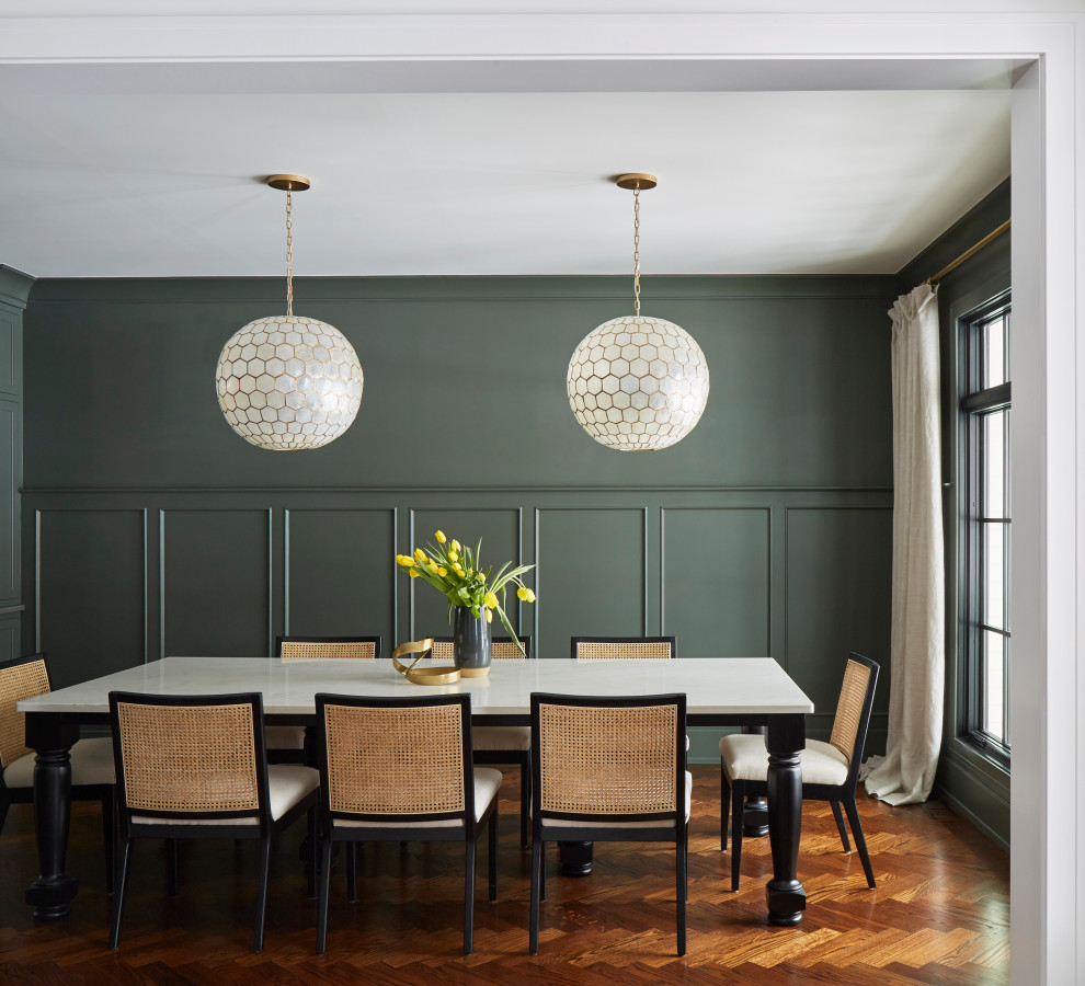 Cette photo montre une grande salle à manger nature fermée avec un mur vert, parquet foncé, aucune cheminée, un sol marron et boiseries.