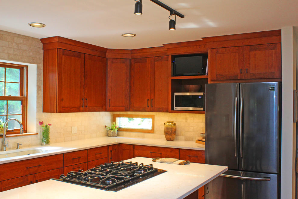 Transitional l-shaped terra-cotta tile and red floor eat-in kitchen photo with an undermount sink, shaker cabinets, medium tone wood cabinets, quartz countertops, beige backsplash, travertine backsplash, stainless steel appliances, an island and beige countertops