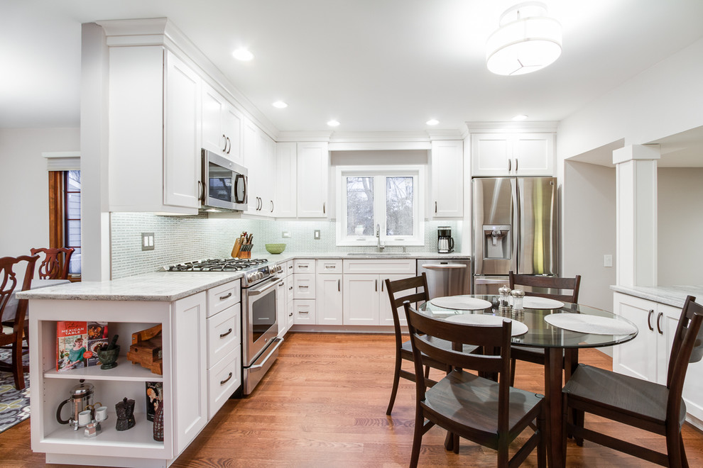 Transitional medium tone wood floor kitchen photo in Chicago with an undermount sink, recessed-panel cabinets, white cabinets, granite countertops, gray backsplash, ceramic backsplash and stainless steel appliances