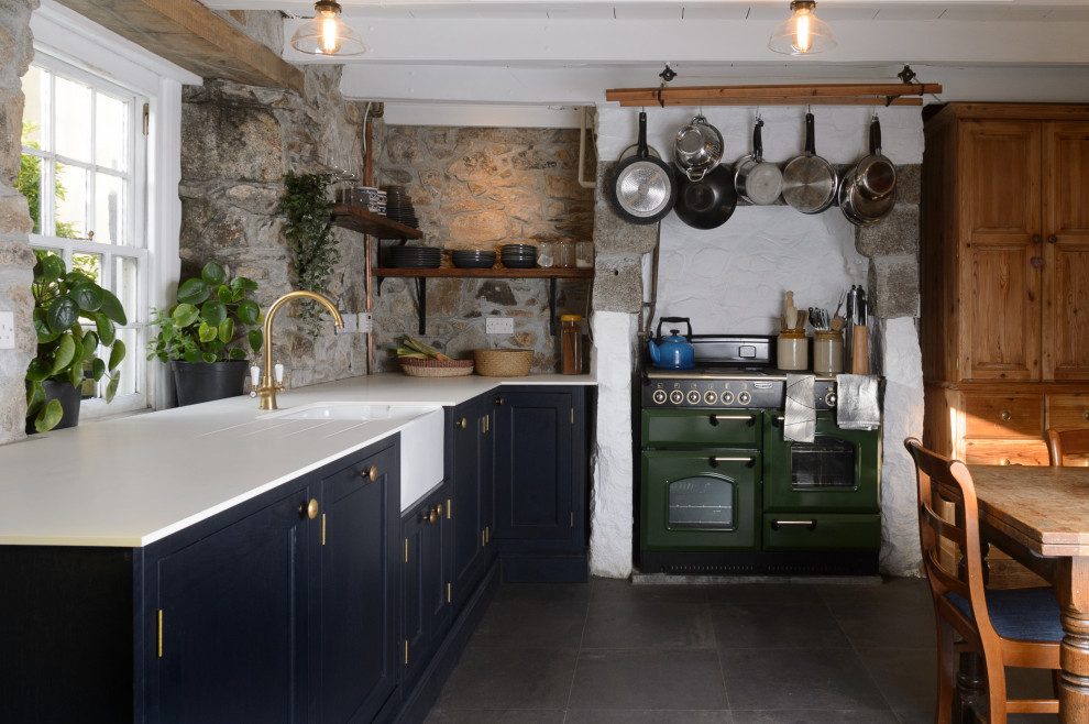 Inspiration for a small cottage l-shaped slate floor and gray floor eat-in kitchen remodel in Cornwall with a farmhouse sink, shaker cabinets, blue cabinets, solid surface countertops, brick backsplash, colored appliances and white countertops