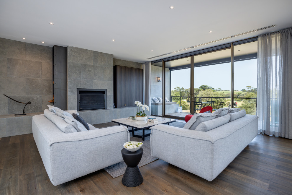 This is an example of a contemporary open concept living room in Melbourne with grey walls, dark hardwood floors, a standard fireplace and brown floor.