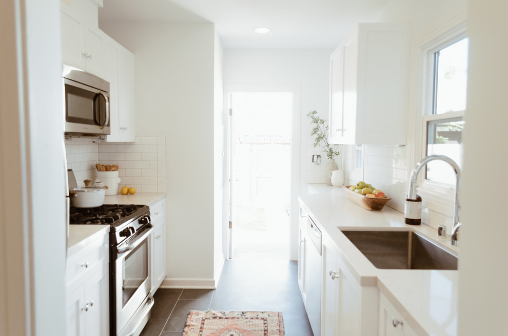 Inspiration for a small beach style galley separate kitchen in San Diego with an undermount sink, shaker cabinets, white cabinets, quartz benchtops, white splashback, subway tile splashback, stainless steel appliances, ceramic floors and no island.