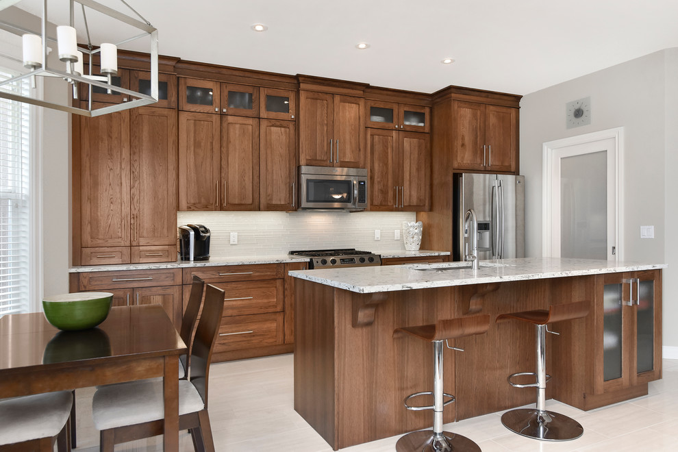 Inspiration for a large transitional single-wall porcelain tile open concept kitchen remodel in Calgary with an undermount sink, medium tone wood cabinets, quartz countertops, beige backsplash, stainless steel appliances and an island