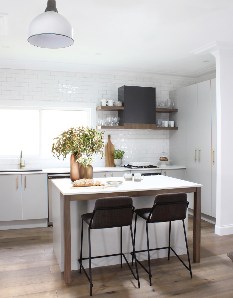 Inspiration for a mid-sized contemporary l-shaped kitchen in Sydney with flat-panel cabinets, grey cabinets, granite benchtops, white splashback, with island, white benchtop, subway tile splashback, panelled appliances, medium hardwood floors and beige floor.